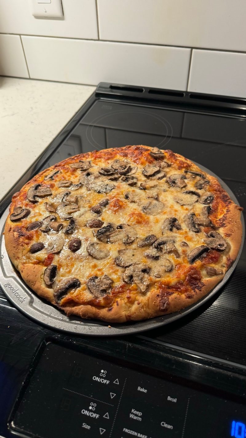 A homemade mushroom pizza fresh out of the oven on a baking pan