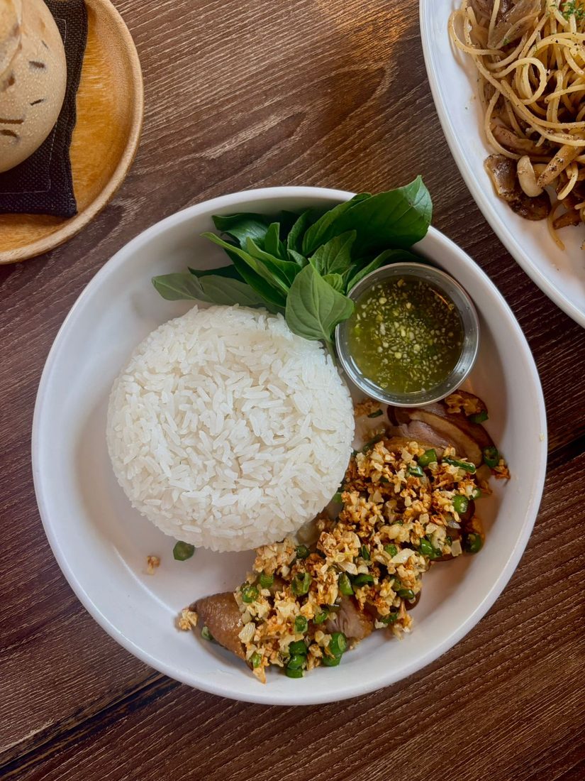 A plate of steamed rice with basil, chili-garlic sauce, and sliced pork, Thai khao man style
