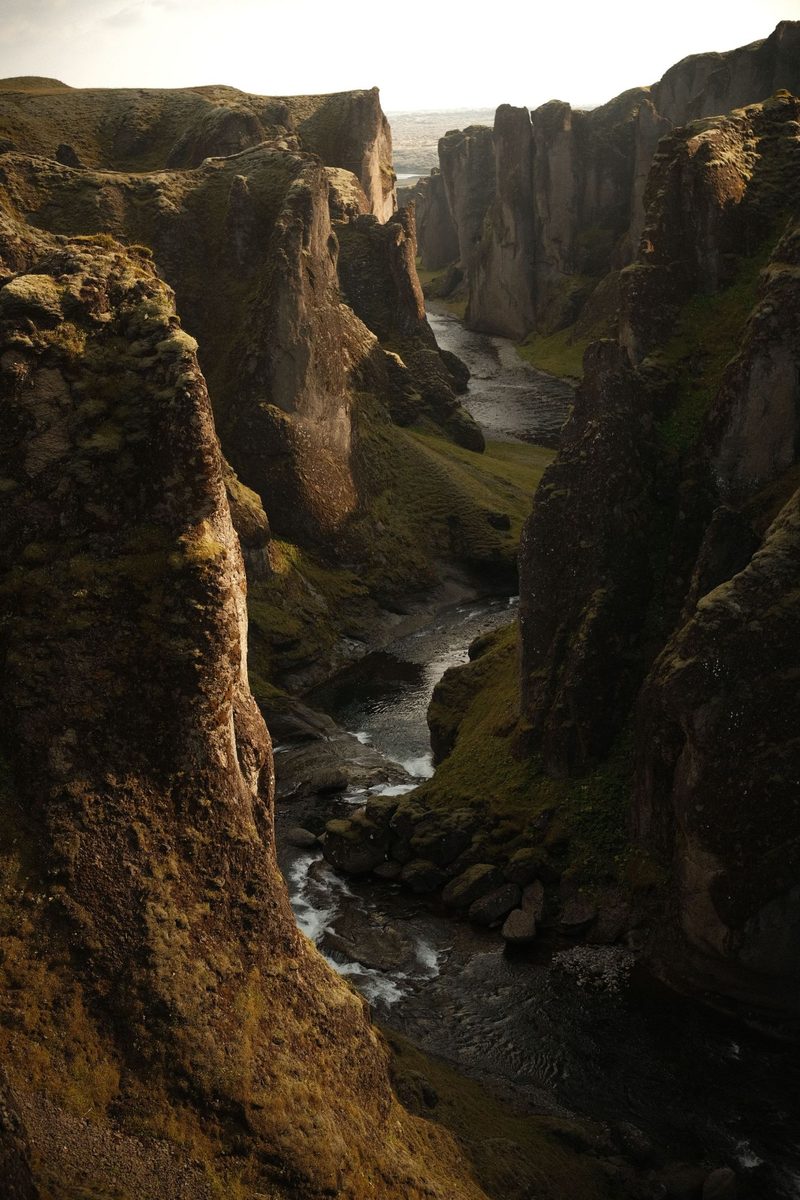 A narrow canyon in Iceland with moss-covered basalt walls and a river cutting through the bottom