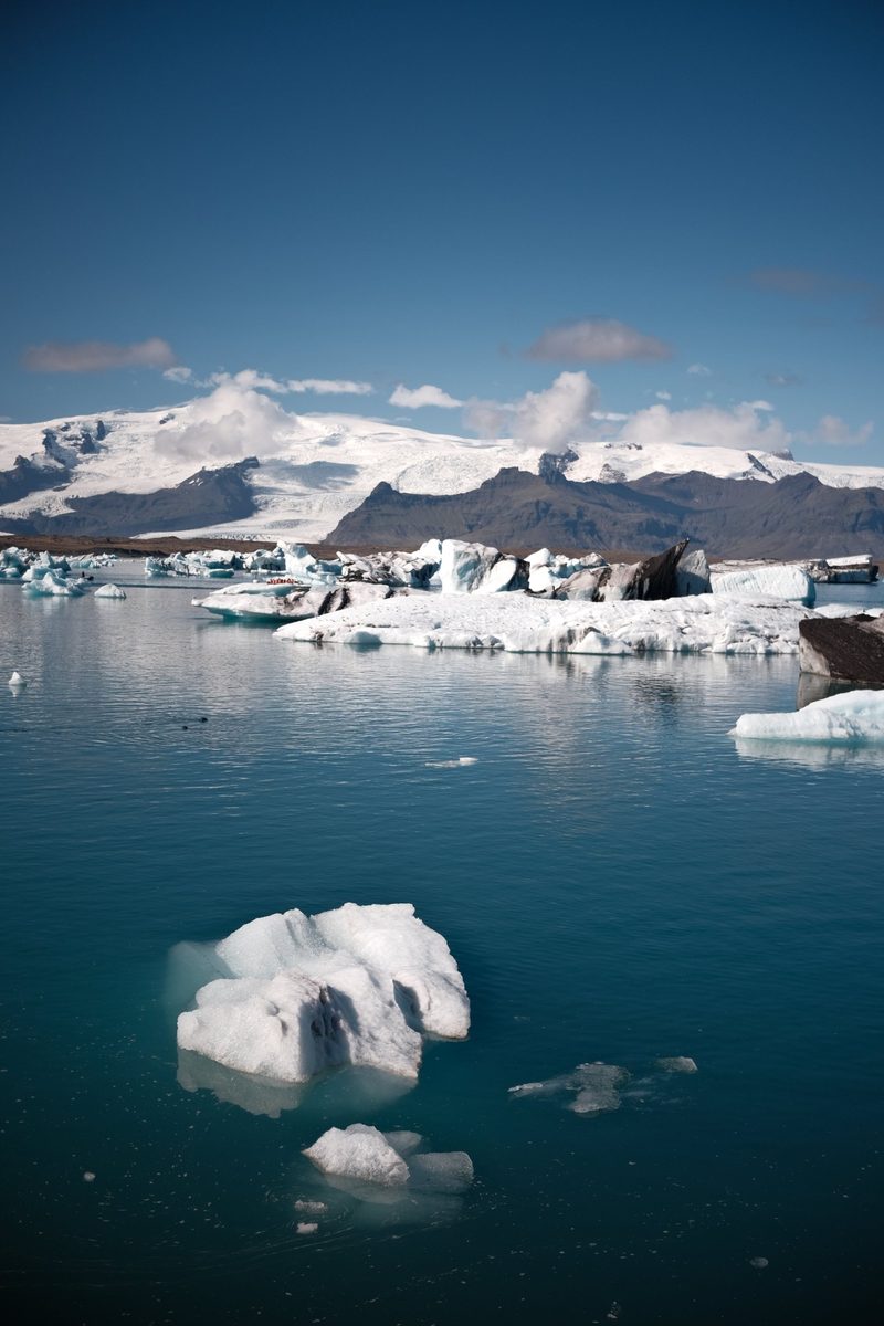 A glacial lagoon in Iceland, icebergs floating on blue water beneath snow-capped mountains